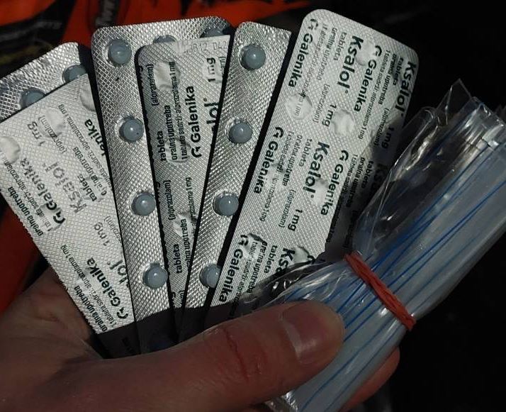 Kädessä on viuhkan muodossa lääkelevyjä sekä rullattuna ja kuminaudalla kiedottuna muovipusseja.