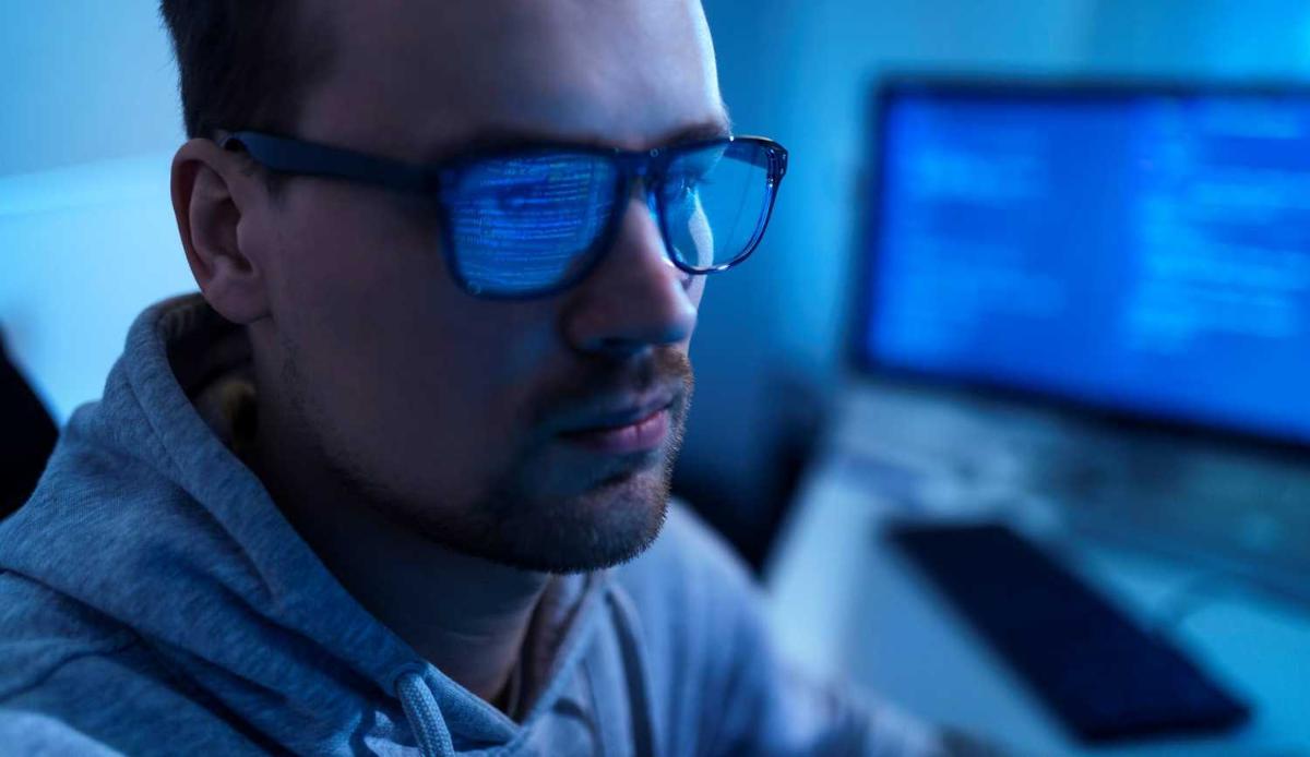 Miehen silmälaseihin heijastuu tietokoneen ruutu