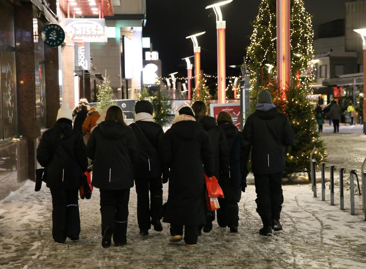 Toppatakkeihin varustautuneet turistit kulkevat ryhmänä kävelykadulla.