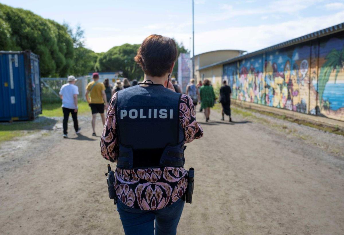 Naispoliisi kävelee poliisin liivi yllään tapahtumassa