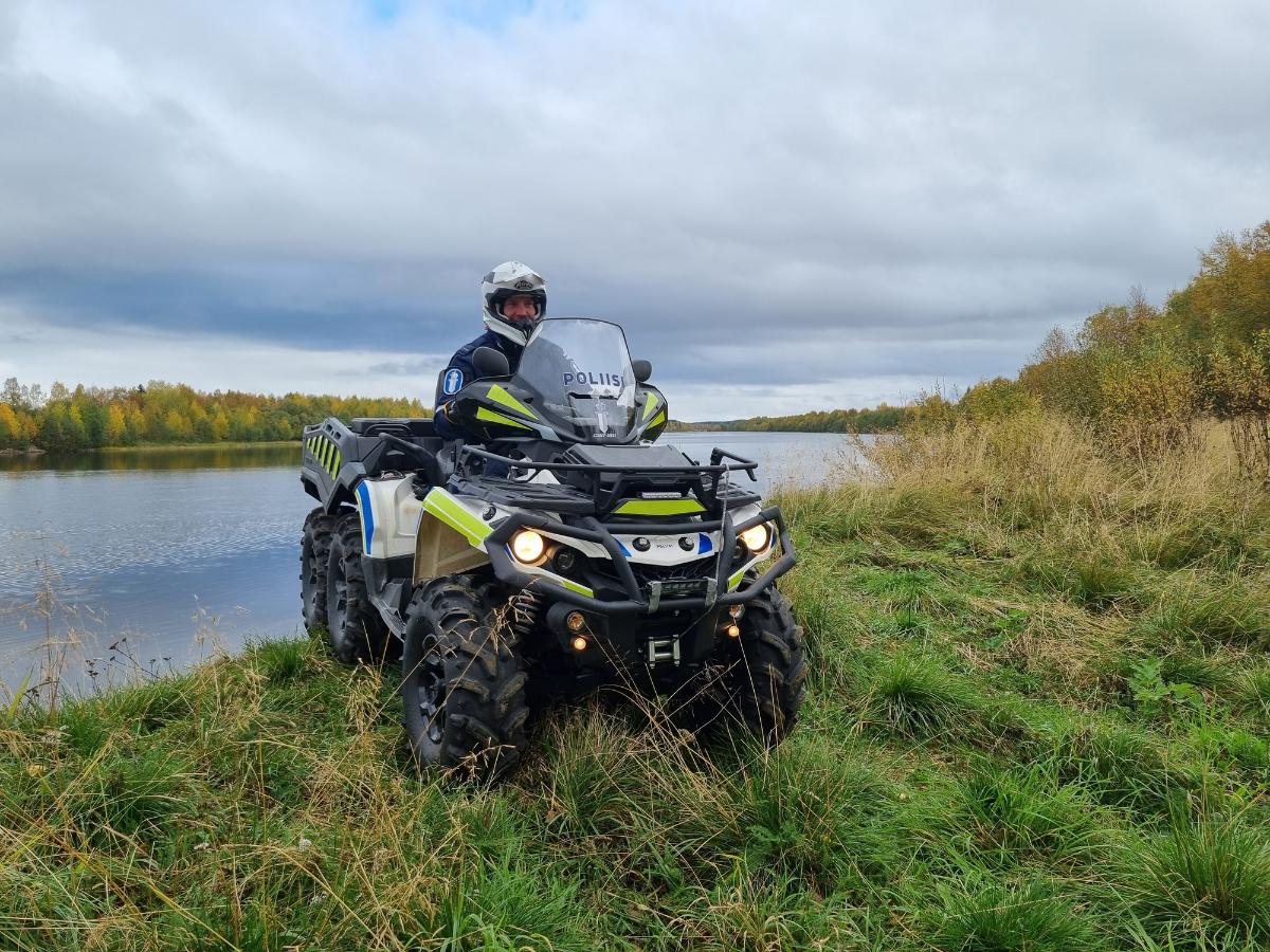 Poliisi istuu mönkijän päällä joen rantatöyräällä syksyllä