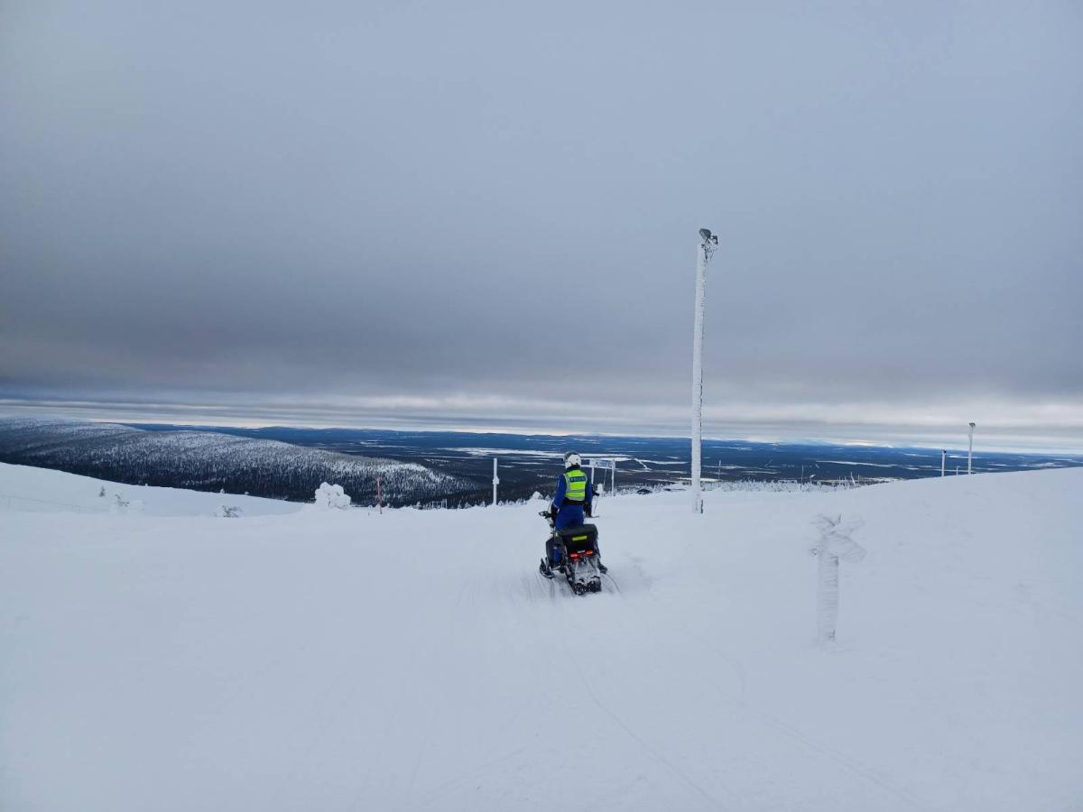 Poliisi on moottorikelkalla tunturin päällä ja tähyää eteenpäin.