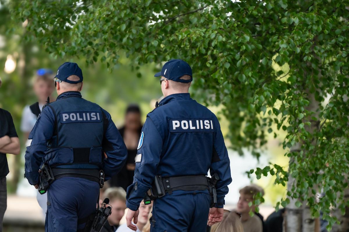 Kaksi poliisimiestä kävelee nuorten keskuudessa.