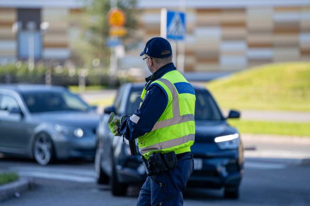 Poliisi kävelee huomioliivit päällä pysäyttämään autoa.