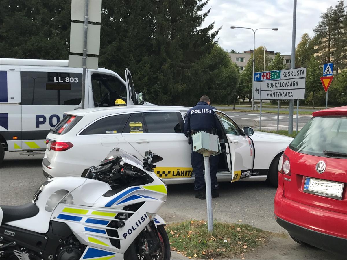 Poliisi kurkistaa taksiin avoimesta matkustajan puoleisesta etuovesta