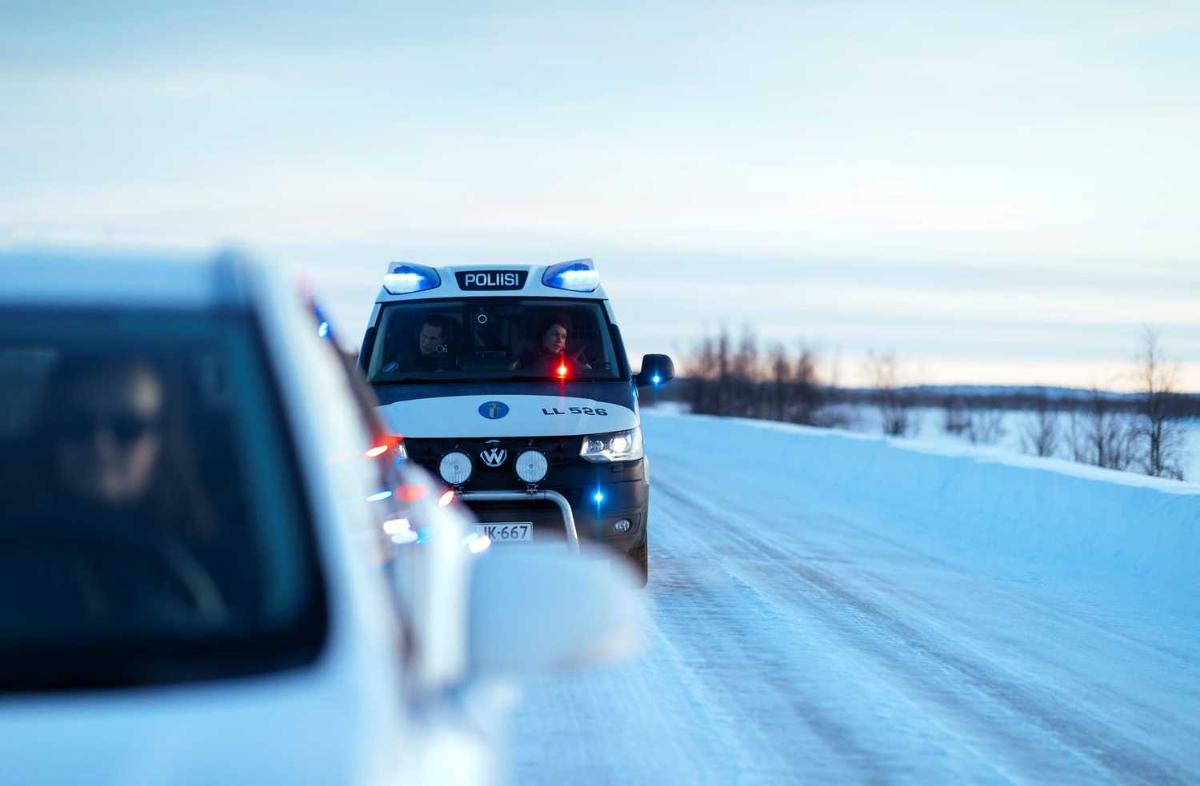 Poliisiauto on pysäyttänyt edellä ajaneen henkilöauton jäisen tien varteen.