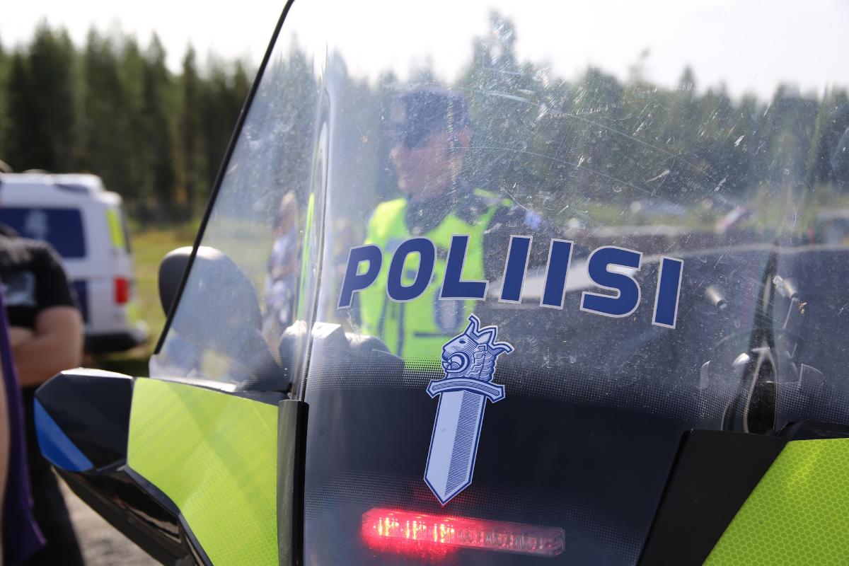 Poliisi ja kansalaisia seisovat poliisin mönkijän takana.