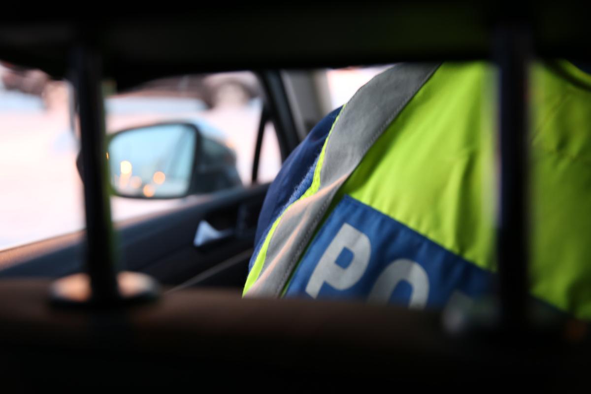 Poliisin huomioliivin selkäosan poliisi-tekstin alkuosaa näkyy hieman auton penkin ja niskatuen välistä