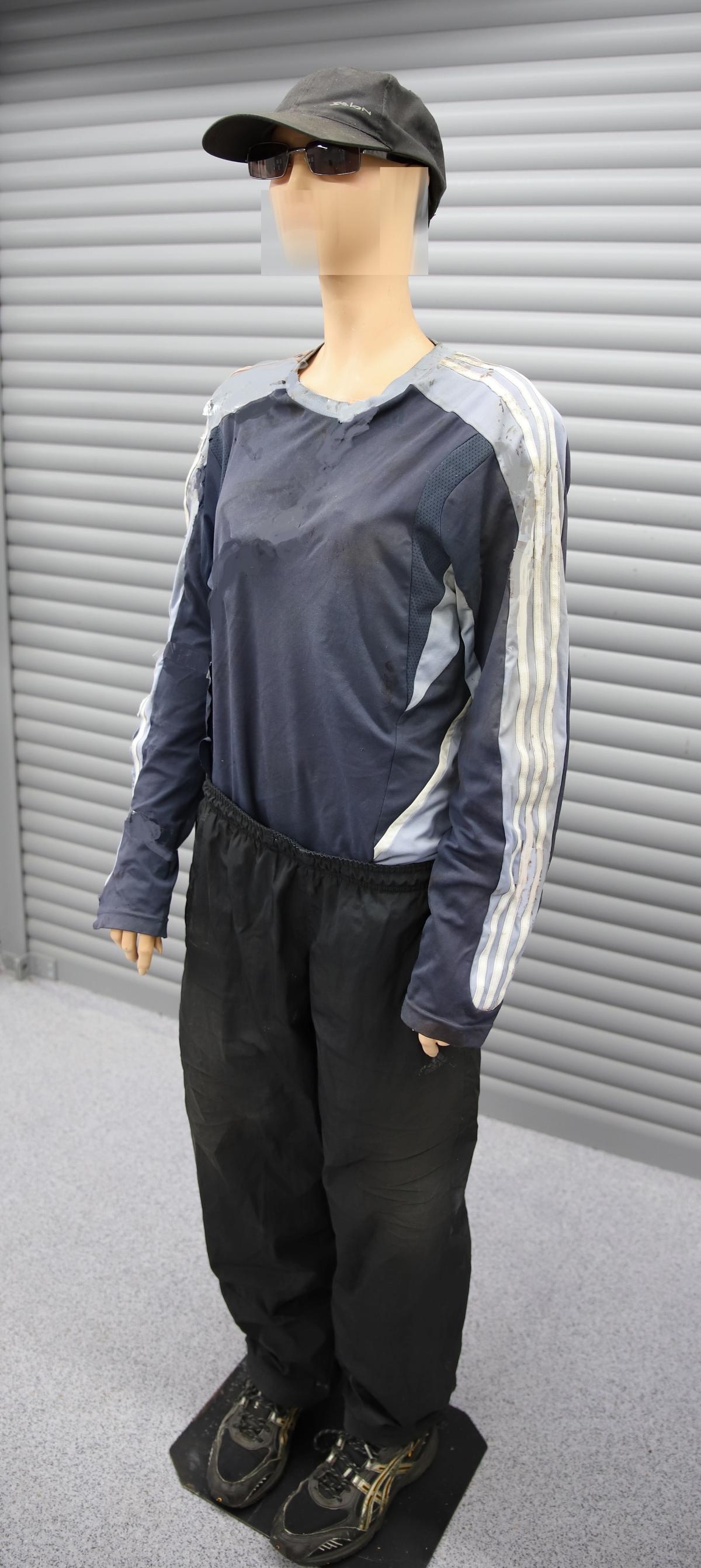 Nukke, jolla päällä mustat tuulihousut ja Adidaksen pusero