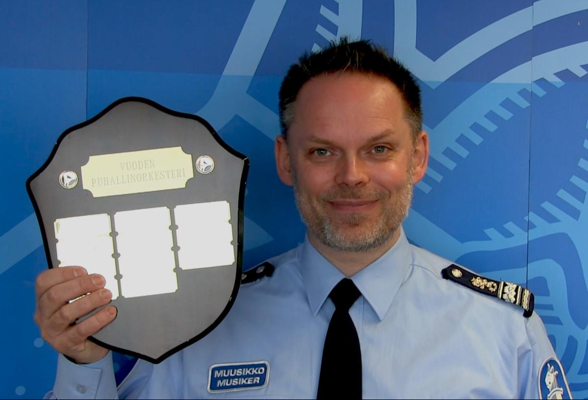 Helsingfors polismusikkårs överkapellmästare håller i handen Årets blåsorkester -pris.