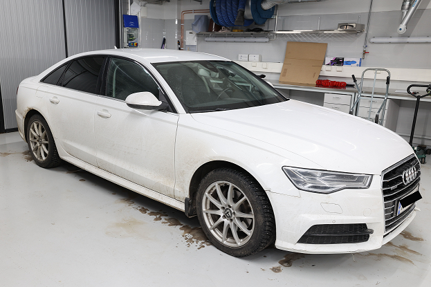 Valkoinen henkilöauto hallissa.