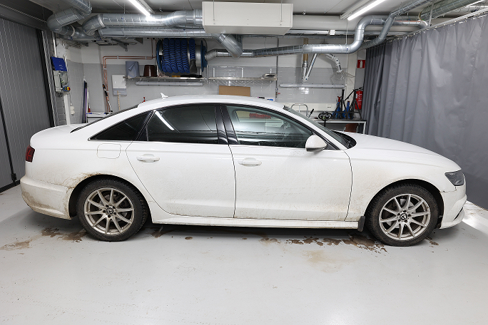 Valkoinen henkilöauto hallissa.