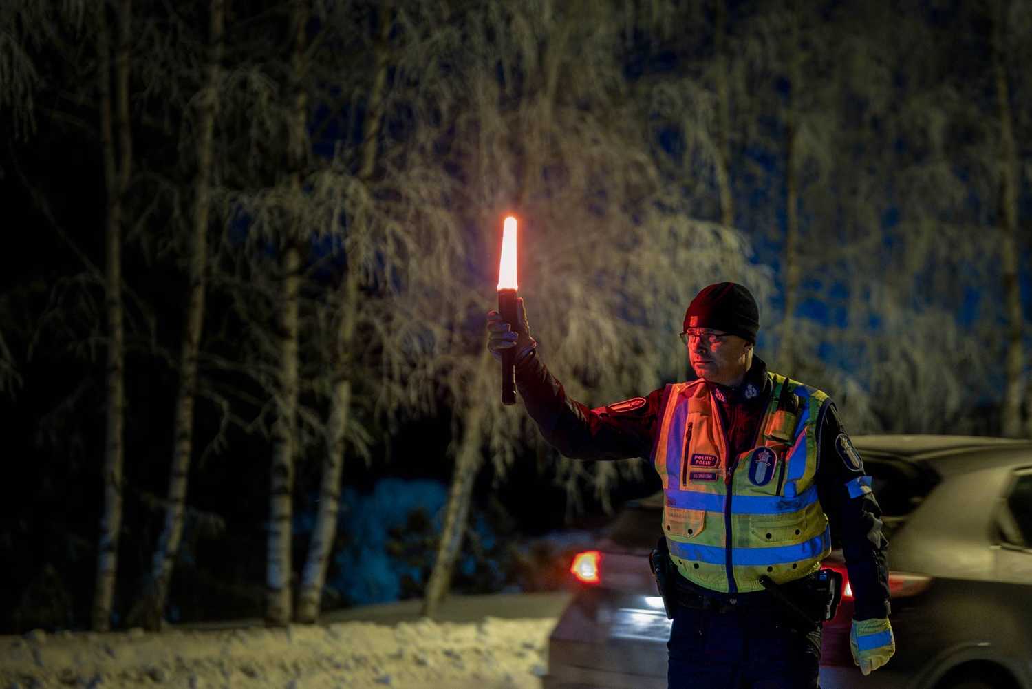 Poliisi pysäyttää ajoneuvoa lumisissa olosuhteissa punaisella pysäytysvalolla.
