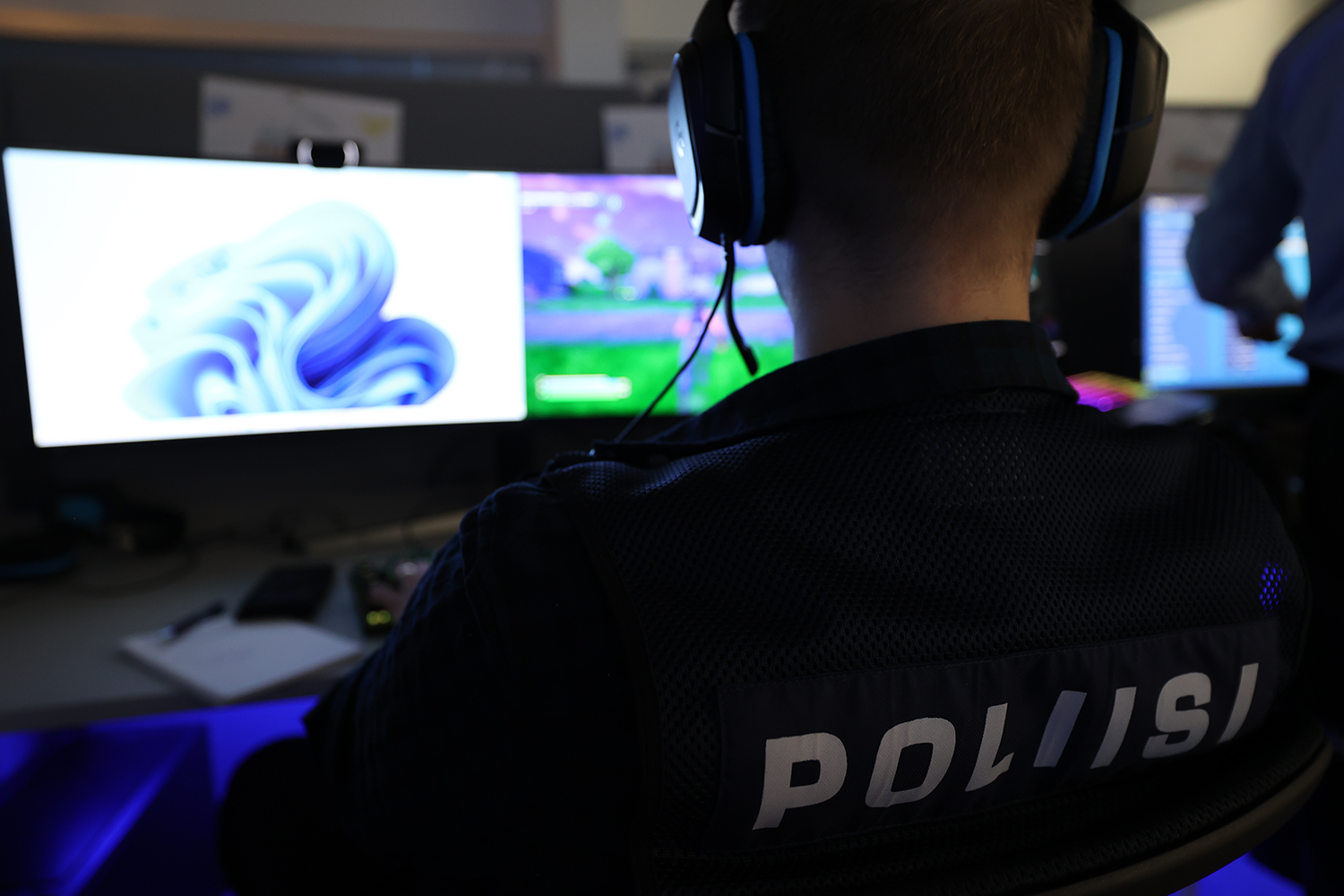 Poliisi pelaamassa tietokonepeliä kuulokkeet korvilla
