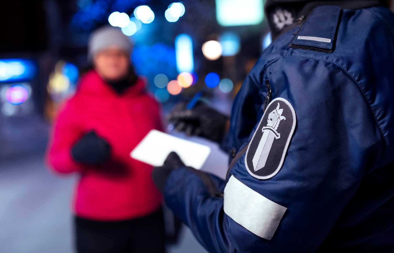 Poliisi jalkautuneena kadulla, kädessä lehtiö, tekee muistiinpanoja.