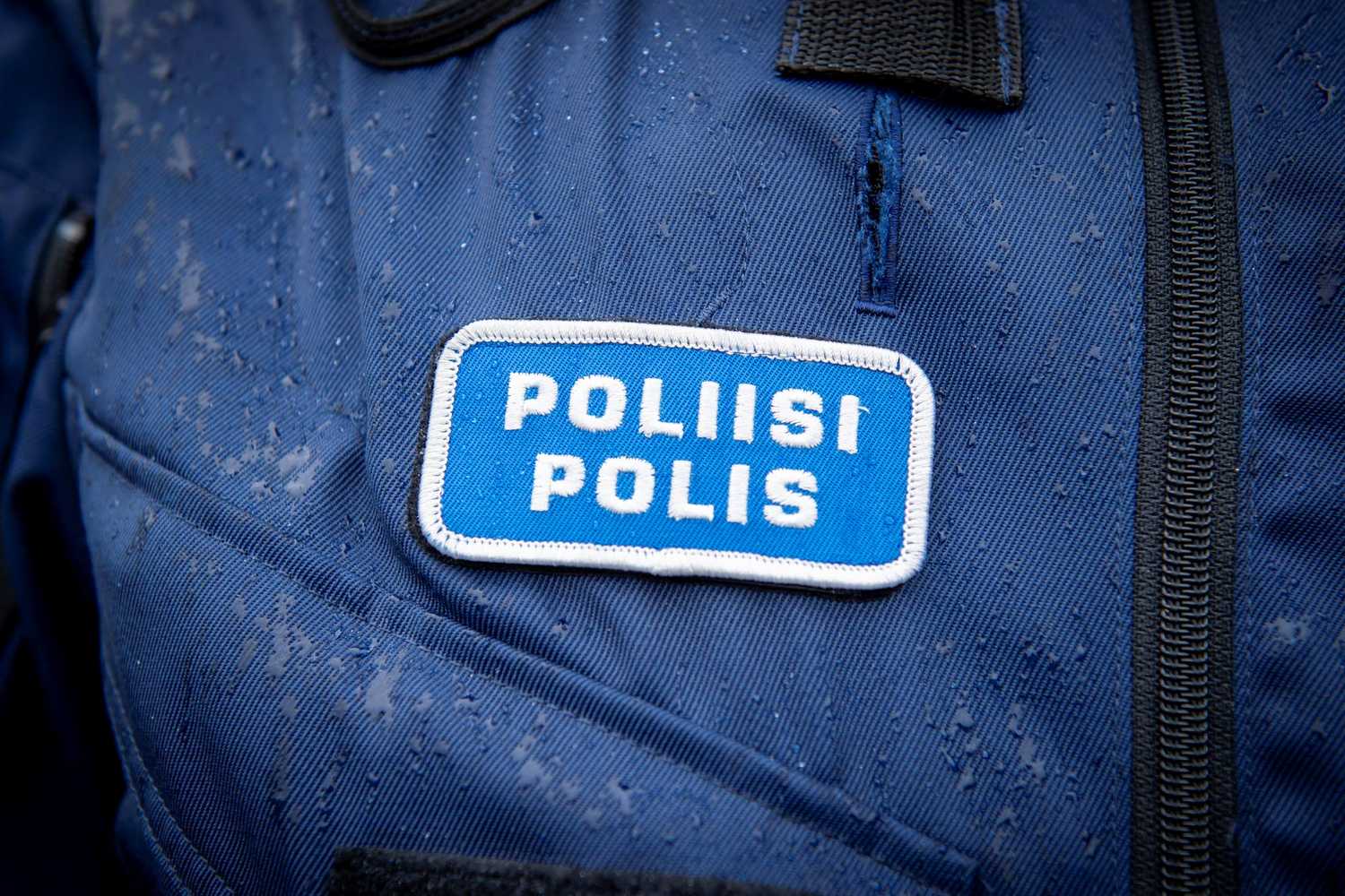 Poliisi/Polis kangasmerkki sateesta kastuneen suojaliivin rinnuksessa.